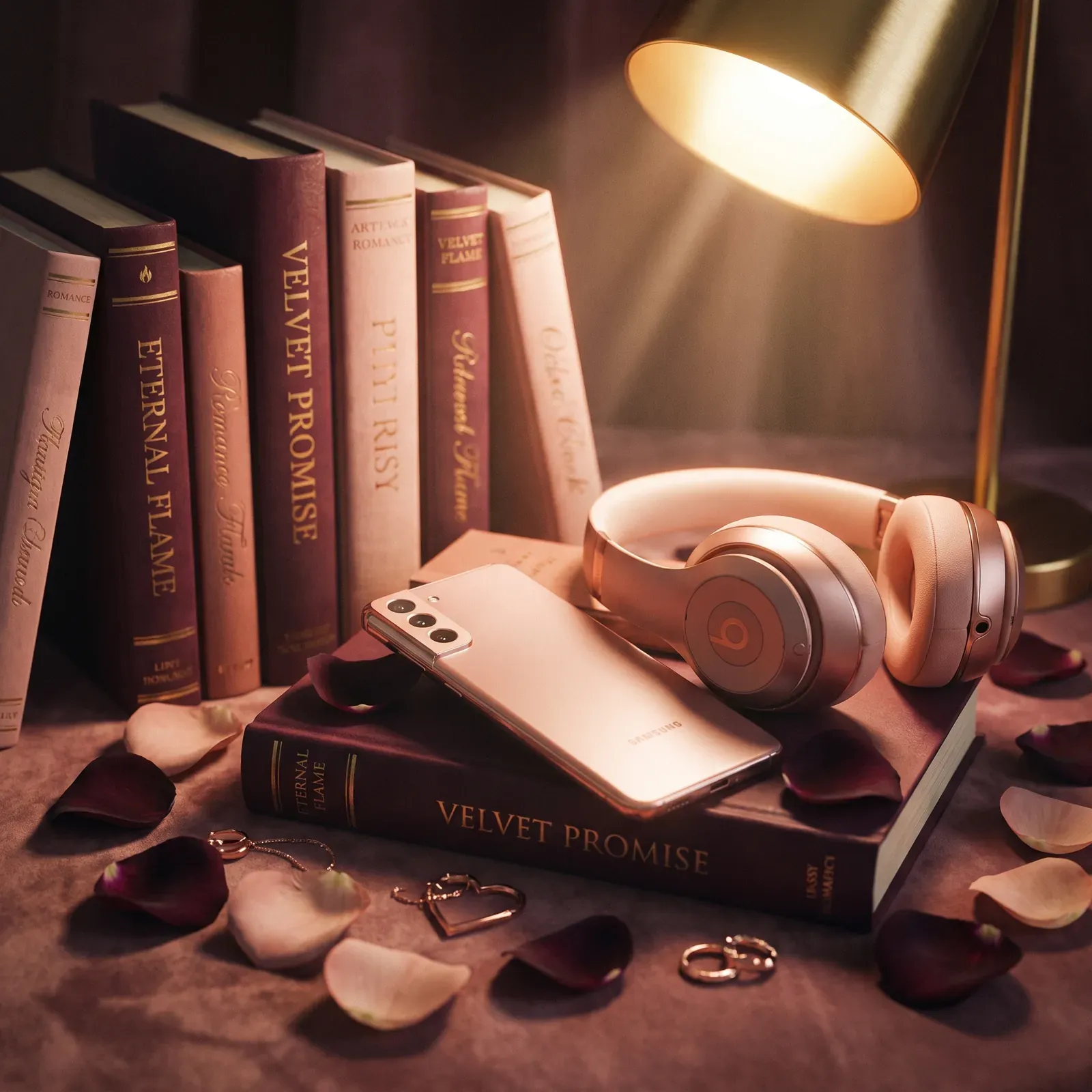 Livros de romance empilhados com fones de ouvido rosados, celular e pétalas de rosa sob um abajur